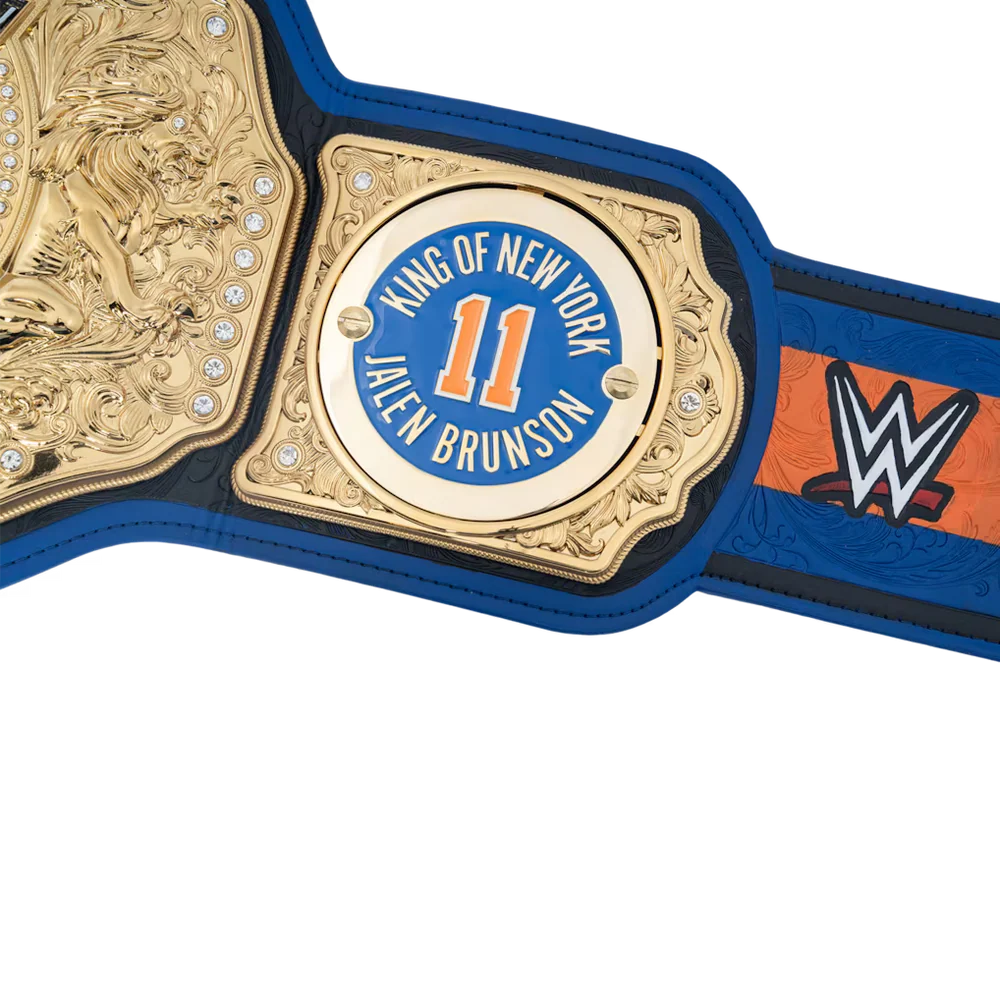Close-up of a blue and black WWE championship belt with ornate gold plates, including a central medallion that reads 'King of New York Jalen Brunson' with the number 11.