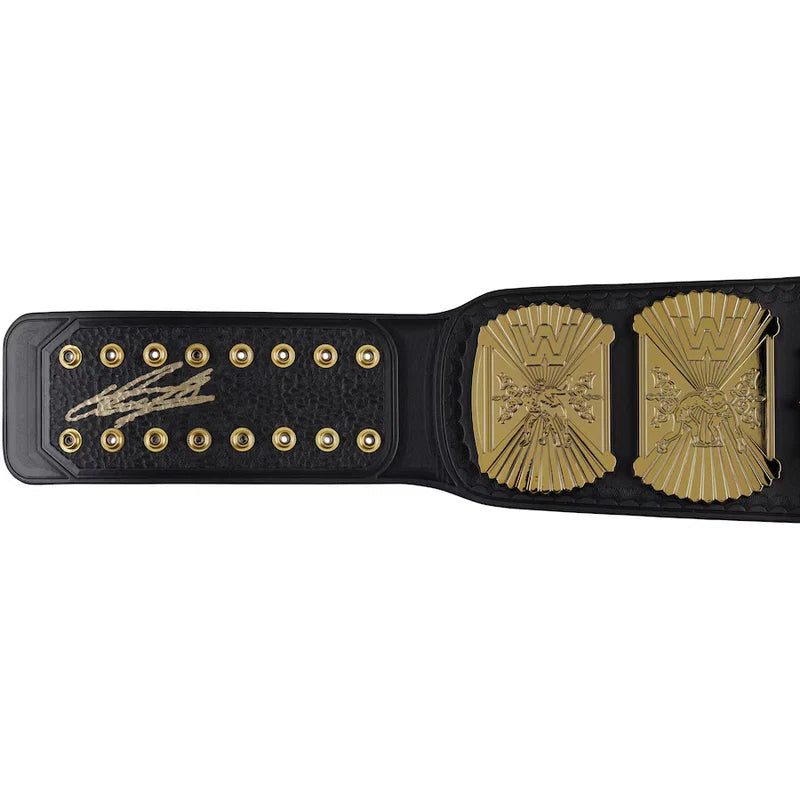 A black leather championship belt with gold-toned hardware, featuring a large ornate gold plate on the right and a gold signature plate on the left, photographed against a plain white background.