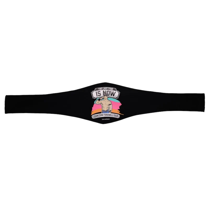 A black athletic waist wrap or belt featuring a colorful graphic in the center with a muscular torso illustration and the text 'THE PLEASANT IS NOW' and 'COMMEMORATE WAISSING'.