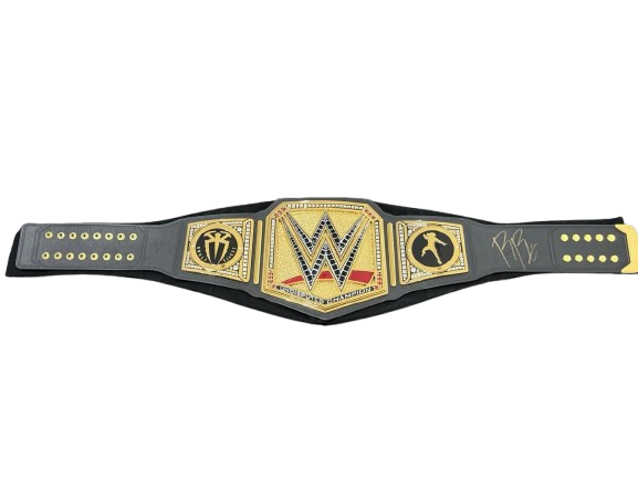 A WWE Championship belt with a black strap and gold-toned metal plates, featuring the WWE logo in the center and signature details on the right side, shown against a plain white background.