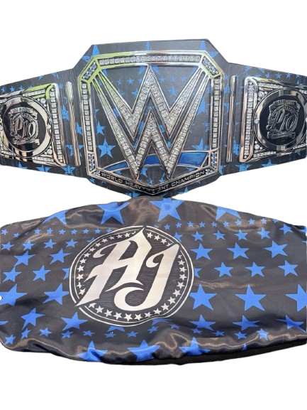 A wrestling championship belt and matching headband set. The belt features a large central silver 'W' with 'Wrestling Entertainment' text, flanked by two side plates with 'W' and 'AJ' logos, all over a black background with blue stars.