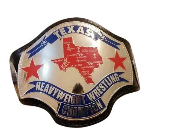 A Texas Heavyweight Wrestling Champion belt buckle featuring a silver-toned background with a red map of Texas, two red stars, and blue banners with white lettering.
