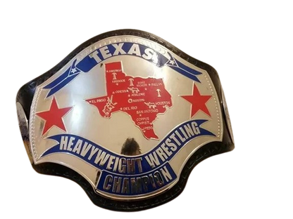 A Texas Heavyweight Wrestling Champion belt buckle featuring a silver-toned background with a red map of Texas, two red stars, and blue banners with white lettering.
