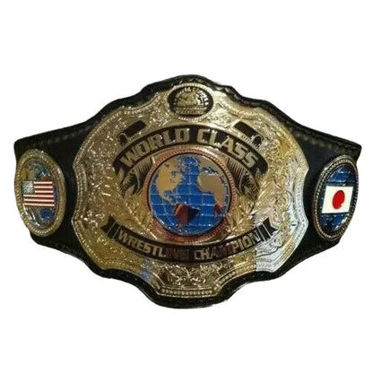 A championship wrestling belt with a large ornate gold-toned central plate reading 'WORLD CLASS WRESTLING CHAMPION,' black side panels, and small circular emblems including an American flag and a Japanese flag, shown on a plain white background.