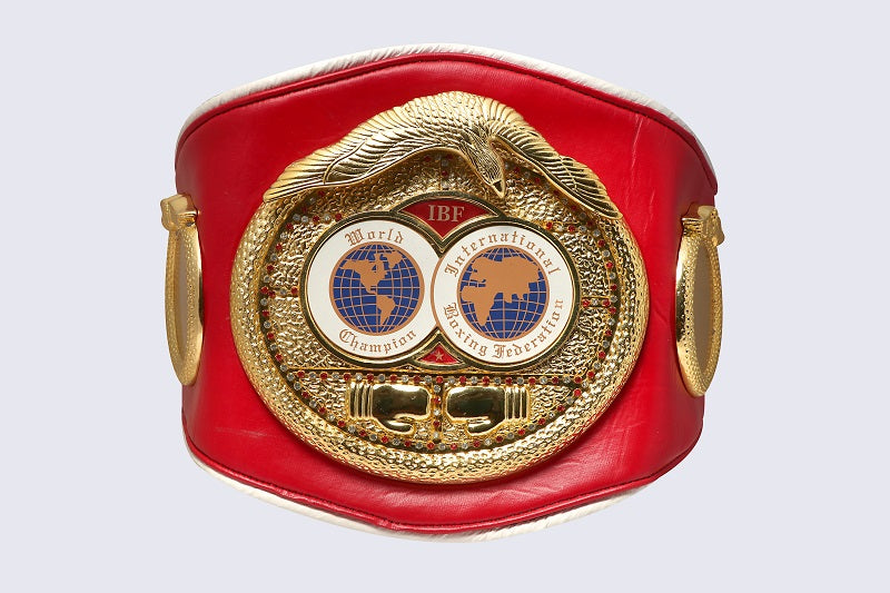 A red boxing championship belt featuring a large gold-colored central medallion with two globe emblems and the text 'IBF International Boxing Federation World Champion'.