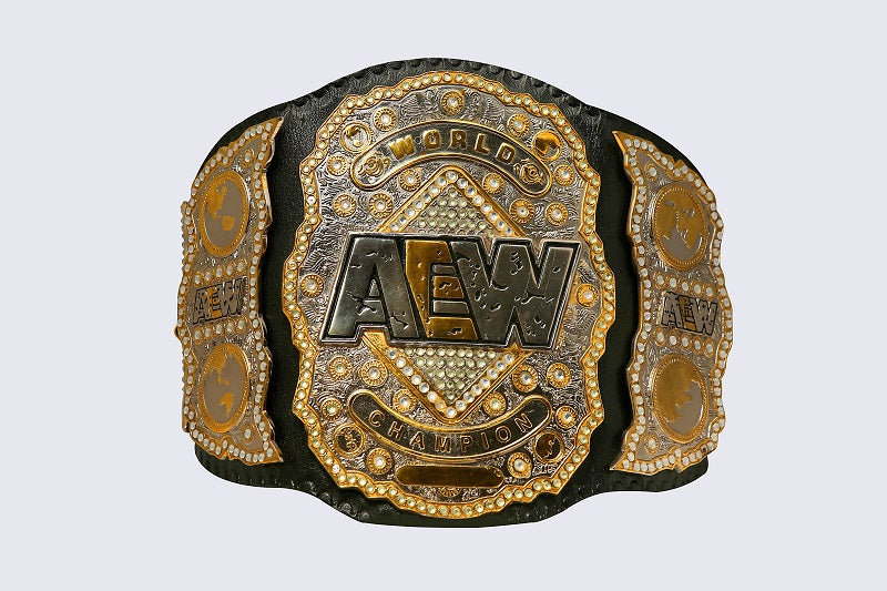 An AEW World Champion belt with ornate gold and silver plates, black leather-like sides, and rhinestone details, centered on a light gray background.