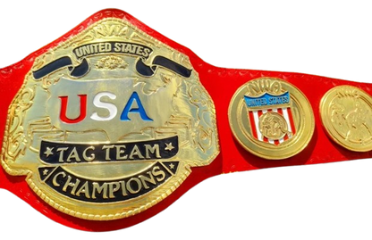 A red and gold USA Tag Team Champions belt with three oval plates, featuring 'USA' in red and blue letters and 'United States' text on a white background.