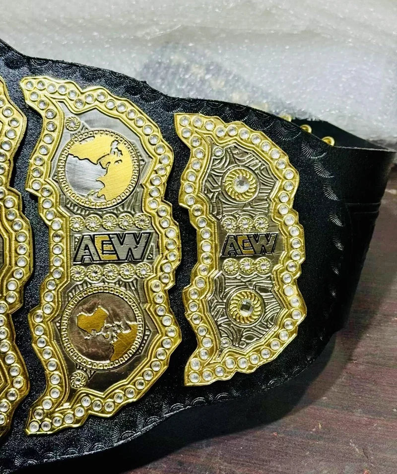 Black championship belt with gold and silver AEW logos on a wooden surface.