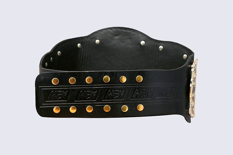 A black leather championship belt with gold and silver studs, featuring the word 'MVP' embossed on the front strap and a large gold-tone buckle, shown against a light gray background.