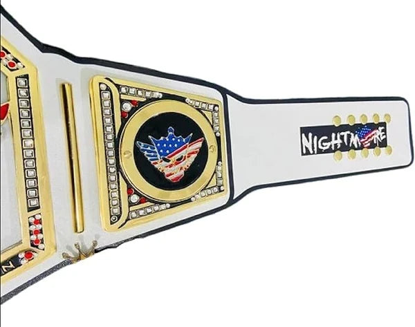 A close-up of a wrestling championship belt strap with a white leather-like base, gold-tone metal plates, black trim, and a central emblem featuring an American flag motif. The right side shows the text 'NIGHTMARE' in white on a black background with gold dots.