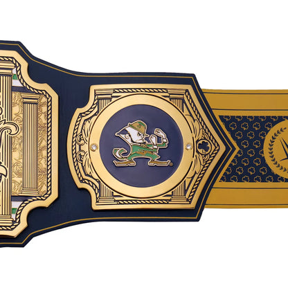 A close-up of a championship-style belt or strap featuring a large central gold-toned medallion with a navy blue circular inset and a green-and-white leprechaun figure. The surrounding sections are navy blue with ornate gold detailing and a gold side panel.