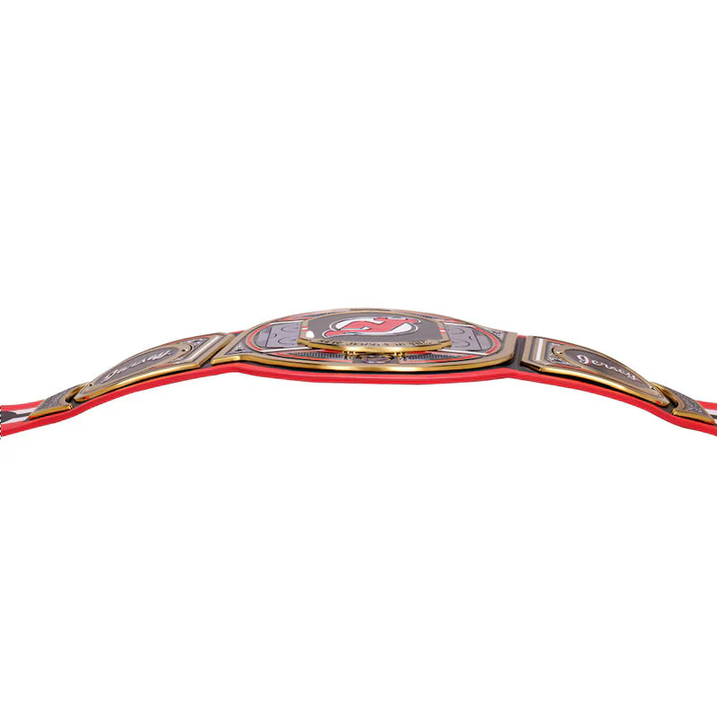 A championship-style belt with a red strap and ornate gold-toned metal plates, shown against a plain white background.