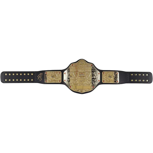 A signed WWE Championship belt signed by Jim Ross, featuring a gold-toned central plate with detailed engravings, flanked by two gold-toned side plates and a black strap with gold studs.