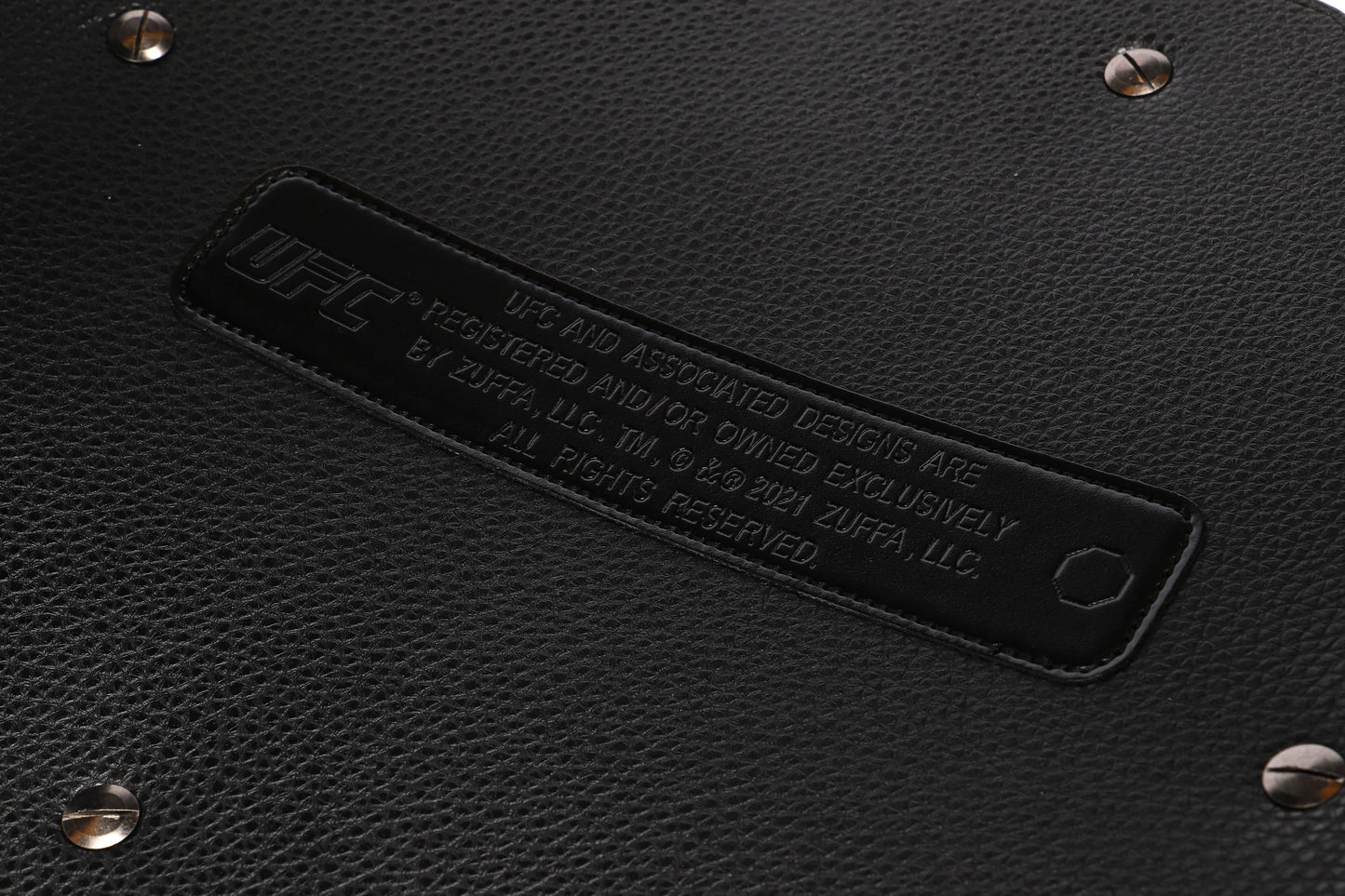 Close-up of a black leather product with a brand label and studs.