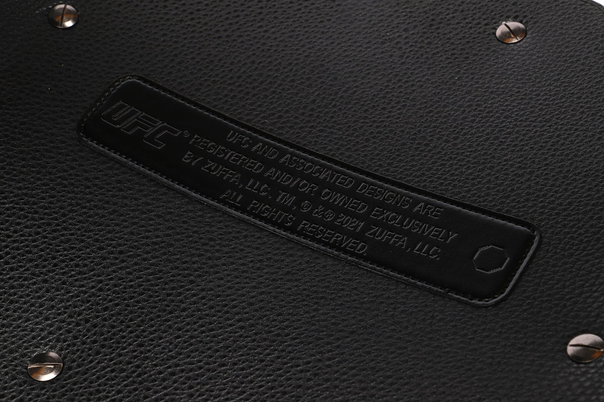 Close-up of a black leather product with a brand label and studs.