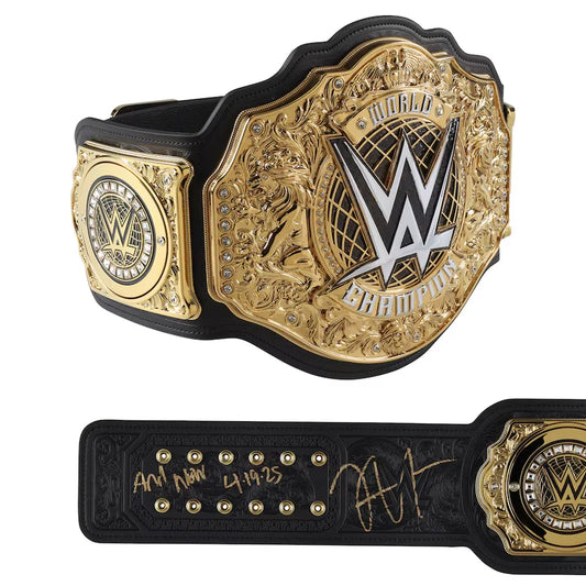WWE Championship belt shown from two angles: a large front view with ornate gold plate, lion motif, and WWE logo, and a shorter rear view showing black strap, gold studs, signature, and date. The belt is photographed on a clean white background.