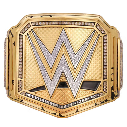 WrestleMania Golden Championship belt featuring a large gold-toned plate with a silver and gold WWE 'W' logo, bordered by clear gemstones, and the text 'WRESTLEMANIA GOLDEN CHAMPION' along the bottom.