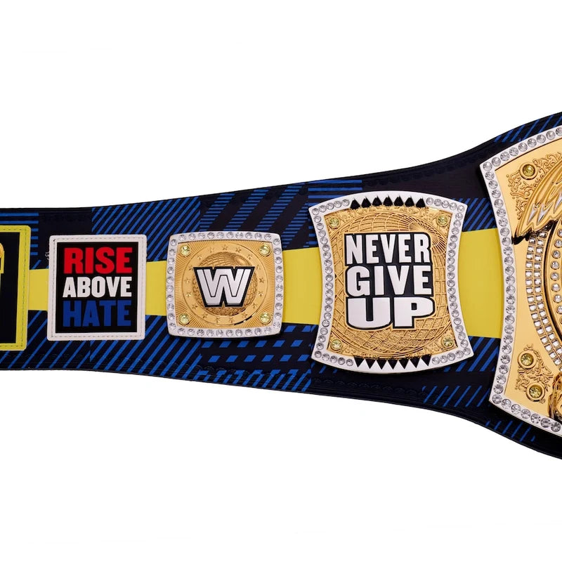 A close-up of a championship-style belt with multiple gold-tone plates, including a central plate reading 'NEVER GIVE UP' and another reading 'RISE ABOVE HATE.' The strap is black with blue diagonal striping, a yellow center stripe, and rhinestone trim.