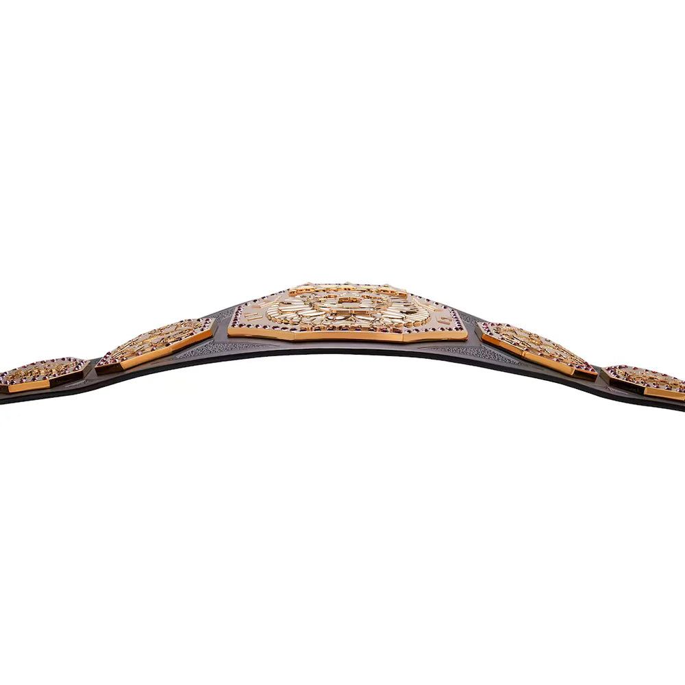 A championship belt with ornate gold-toned plates, dark brown leather straps, and rows of small clear stones, photographed against a plain white background.