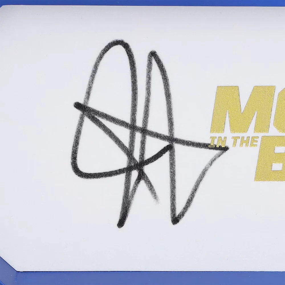 A close-up of a white card featuring a black ink autograph and partial gold text reading 'M.