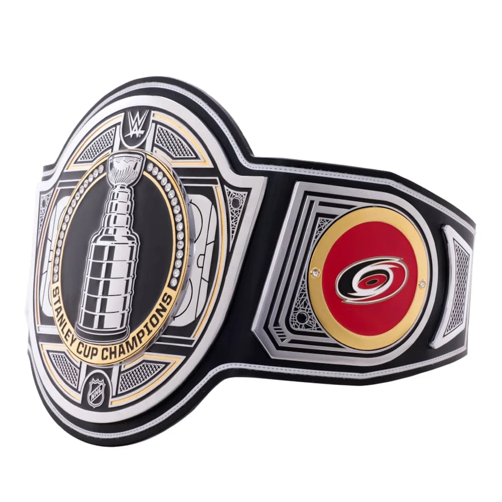 A black and silver NHL Stanley Cup Champions championship belt featuring the Stanley Cup trophy emblem on the front and the Carolina Hurricanes logo on the side, shown on a plain white background.