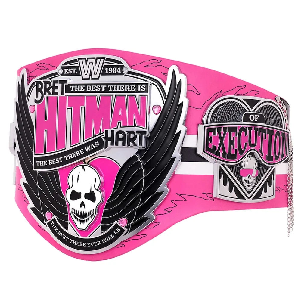 A pink and black Bret Hart 'Hitman' championship belt with silver-toned metal plates, a skull graphic, and a small hanging chain, shown on a plain white background.
