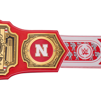 A close-up of a WWE championship belt featuring a red strap with ornate gold plates, a large white letter N in the center, and a WWE logo on the end, set against a plain white background.