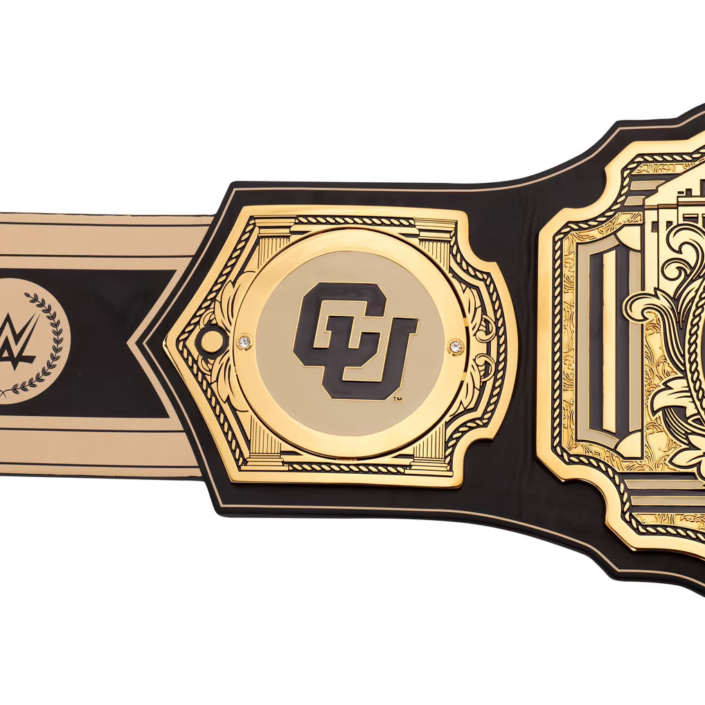 A close-up of a championship belt featuring a central gold plate with a black 'CU' logo, flanked by black and gold side plates, on a plain white background.