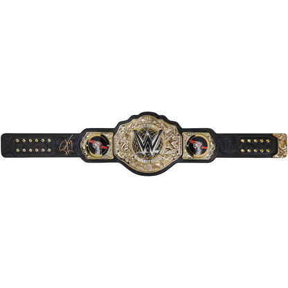 A WWE championship belt with a large ornate gold and silver central plate, flanked by two smaller gold plates, all mounted on a black strap, shown against a plain white background.