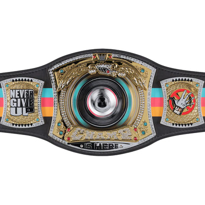 A highly detailed championship belt featuring a large central gold-toned winged medallion with a spinning black, silver, and red disc. The belt strap is black with turquoise, pink, and orange stripes, and includes two side plates with silver and gold designs and text reading 'NEVER GIVE UP' and 'U ME'.