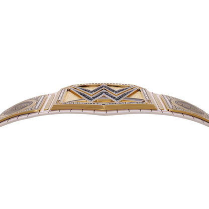 A close-up of a two-tone metal bracelet featuring a gold and silver-tone band with a central geometric diamond pattern embellished with small dark blue stones.