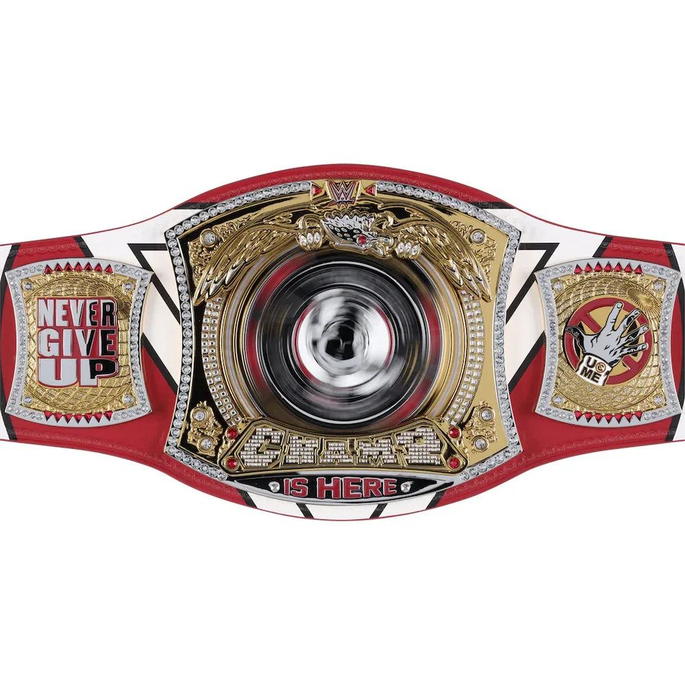 A championship belt with a red, white, and gold design, featuring a large central circular medallion and two side plaques with text including 'NEVER GIVE UP' and 'IS HERE'.