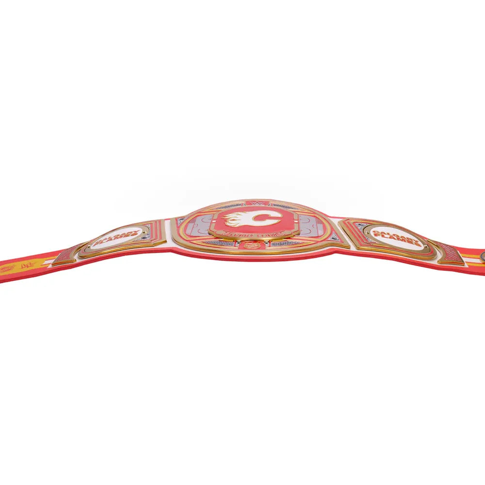 A red and gold championship belt with a central shield emblem and side panels, photographed against a plain white background.
