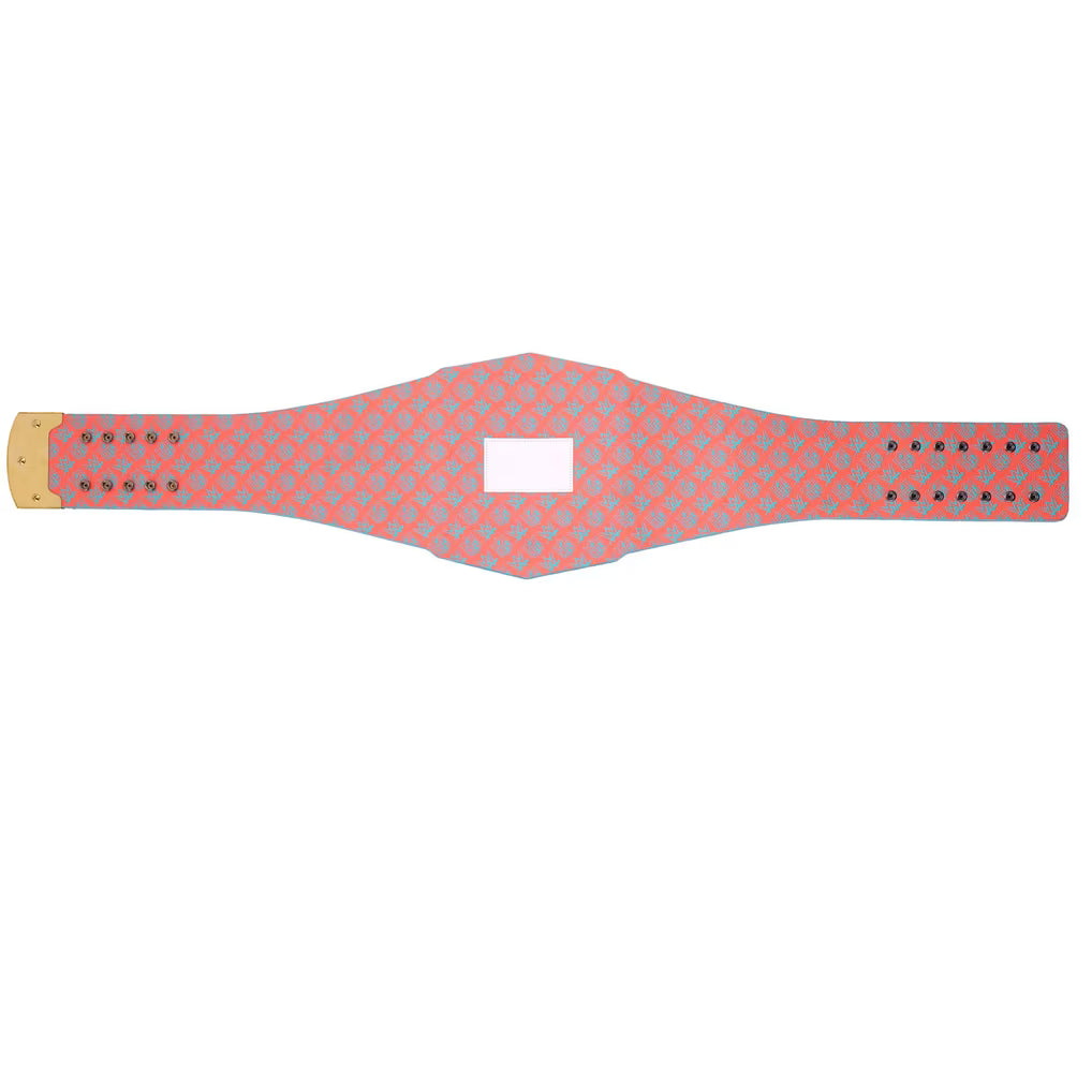 A wide, flat strap-like product with a coral pink and light blue geometric pattern, shown on a plain white background. It has metal grommets on both ends and a blank white rectangular patch in the center.