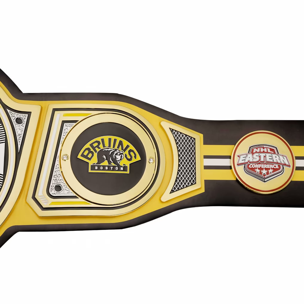 A close-up of a hockey championship belt featuring the Bruins Boston logo and an NHL Eastern Conference patch, shown on a plain white background.