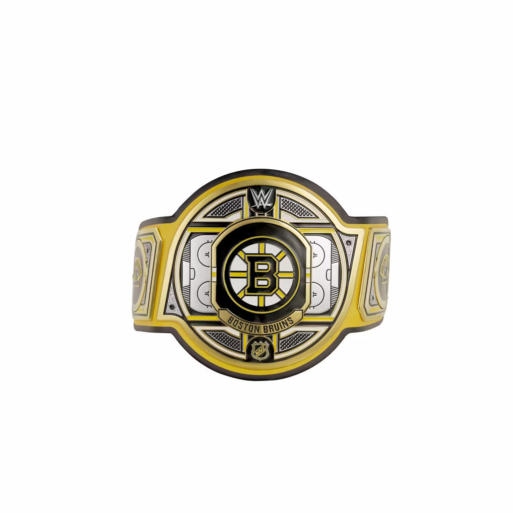 A Boston Bruins NHL championship-style belt buckle or ring centerpiece shown on a plain white background. The design features a large circular center with a black Boston Bruins 'B' logo, surrounded by gold and silver geometric panels and the text 'BOSTON BRUINS.