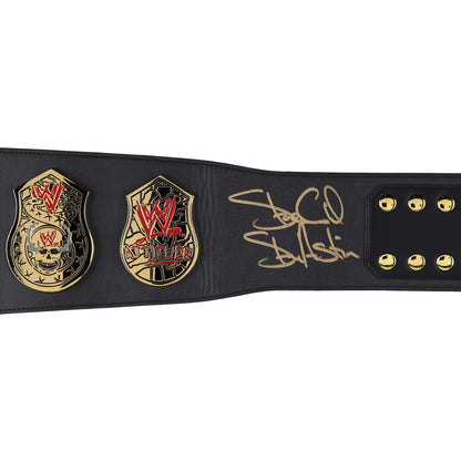 A black leather WWE Championship belt featuring two gold-tone championship plates with red and black detailing, and a gold signature on the strap, shown against a plain white background.