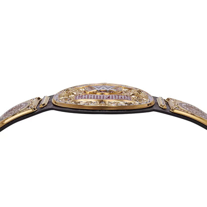 A close-up of a championship belt featuring a gold-toned central plate with 'CHAMPIONS' in purple lettering, flanked by ornate side plates and a black strap, shown against a plain white background.