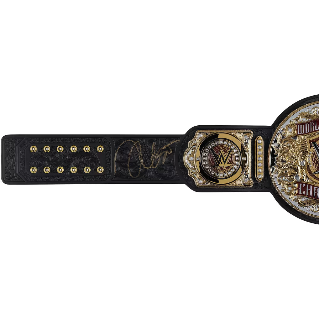 A black and gold WWE Championship belt with an engraved signature, shown horizontally against a plain white background.