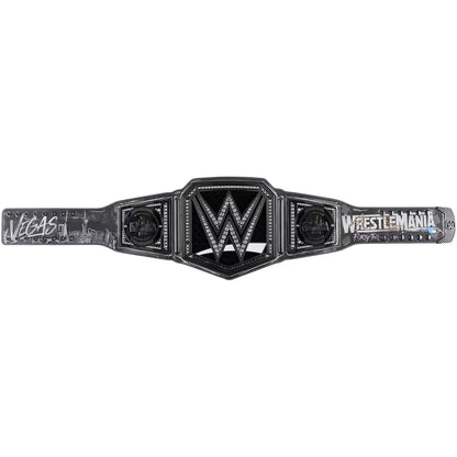 WrestleMania Las Vegas 2024 WWE Championship belt shown flat against a white background, featuring a black and silver central plate with the WWE logo and 'WrestleMania' text on the straps.