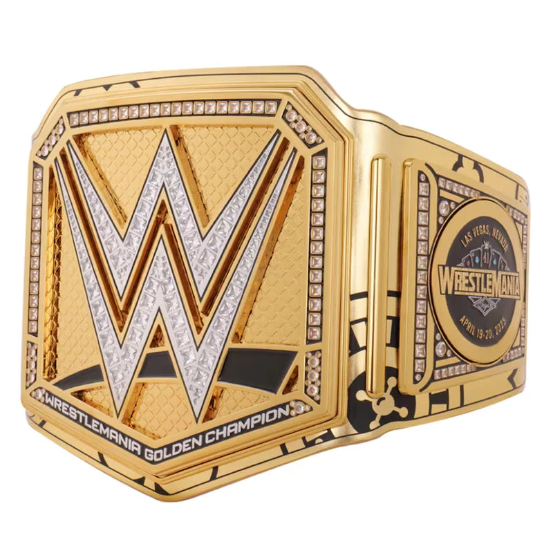 A gold-tone WWE Championship belt with a large textured gold plate featuring a silver and gold 'W' logo, rhinestone borders, and a round medallion on the side, shown on a plain white background.