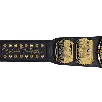 A black leather championship belt featuring a large gold-toned metal centerpiece with a stylized 'W' emblem, a matching side plate, and a black strap with gold studs and a signature on the underside.