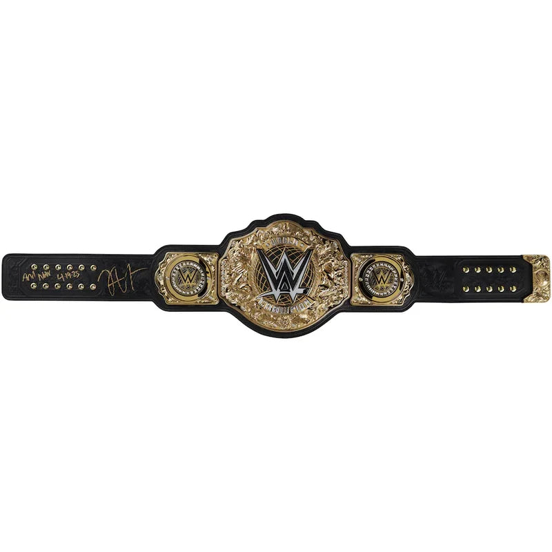 An autographed WWE Championship belt featuring a black leather strap with gold and silver-toned metal plates, signed in silver ink by CM Punk.