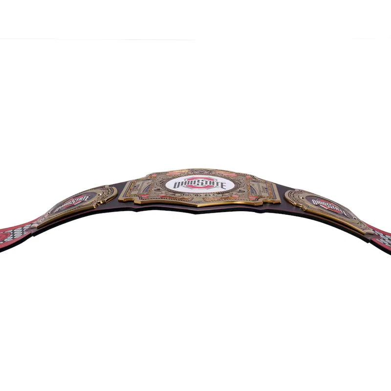 A professional wrestling championship belt, specifically the IWGP World Heavyweight Championship, featuring a large central gold-toned plate with red and white lettering, flanked by two smaller gold-toned plates on a black strap, shown against a plain white background.