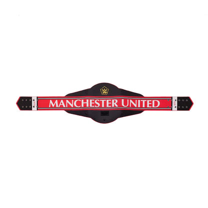 A Manchester United themed belt-shaped wall sign or plaque, featuring a black central body, a bold red horizontal band with 'MANCHESTER UNITED' in white text, and silver-toned metal end caps on a plain white background.